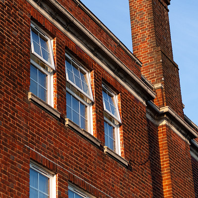The image features a large brick building with two windows on each side. One of the windows is located near the top, while the other is situated in the middle of the building. A chimney can be seen at the top right corner of the building, adding to its architectural charm.