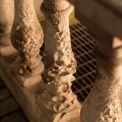 The image features a set of stone stairs with an iron railing. The railing is adorned with intricate carvings, giving it an old and ornate appearance. A metal grate can be seen in the middle of the railing, providing additional support to the structure.