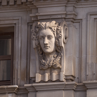 The image features a building with an ornate stone carving of a woman's face on the side. This intricate design adds character and beauty to the structure, making it stand out as a unique architectural feature.