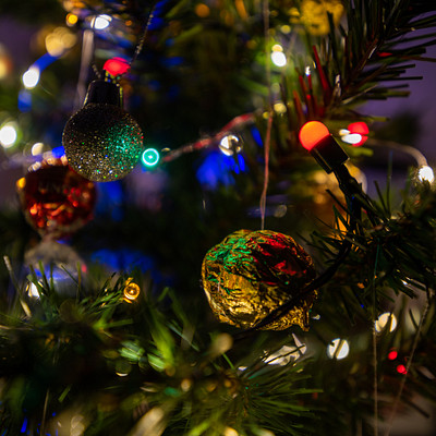 The image features a beautifully decorated Christmas tree with various ornaments hanging from its branches. There are numerous colorful balls and other decorations adorning the tree, creating a festive atmosphere. The tree is filled with lights that illuminate the scene, making it an eye-catching display.