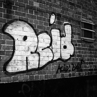 The image features a brick wall with graffiti written on it. The graffiti consists of the word "REDI" in large letters, covering most of the wall's surface. The wall is located next to a window, which can be seen in the background.