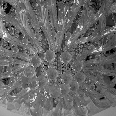 The image features a large, ornate chandelier with many glass beads and crystals. The chandelier is made of clear glass, giving it an elegant appearance. It appears to be hanging from the ceiling, illuminating the space below.