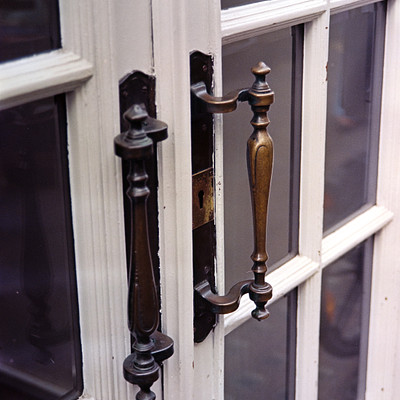 The image features a window with two old-fashioned door handles or locks. These handles are made of wood and have metal parts, giving them an antique appearance. They appear to be attached to the window frame, possibly for security purposes.