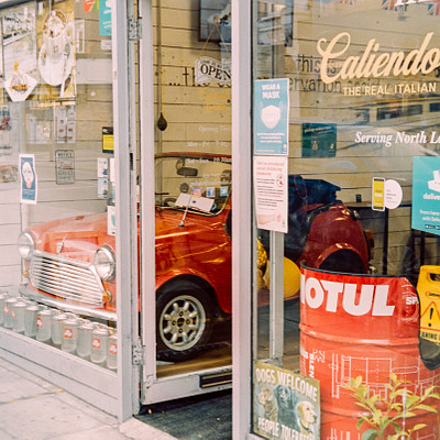 The image features a storefront with a display window showcasing an old-fashioned car. The car is parked inside the glass case, drawing attention to itself as a unique and interesting exhibit. In addition to the car, there are several other items displayed in the storefront.