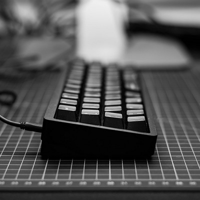 A black keyboard is sitting on a white table. The keyboard has many keys, including the letters and numbers that are typically found on a standard keyboard layout.