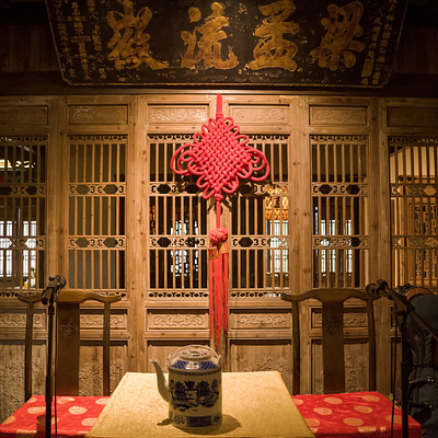 The image features a room with an oriental theme, decorated in red and white. A table is set up with a blue vase on it, surrounded by chairs. There are several other vases placed around the room, adding to the overall decoration.