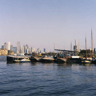 The image features a large body of water with several boats docked in the harbor. There are at least 12 boats visible, ranging from small to large sizes and varying in distance from the shore. Some boats are closer to the foreground while others are further away, creating an interesting scene of different vessels gathered together.