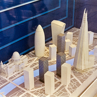 The image features a model of a city with several skyscrapers and buildings. The model is made out of Legos, giving it an intricate and detailed appearance. There are at least 13 buildings visible in the scene, including some that resemble the Space Needle and other iconic structures.