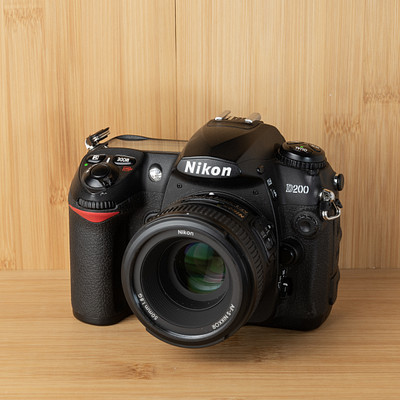 The image features a black Nikon camera sitting on top of a wooden table. The camera is placed in the center of the scene, with its lens facing towards the viewer. The wooden surface provides an appealing backdrop for this photography equipment.