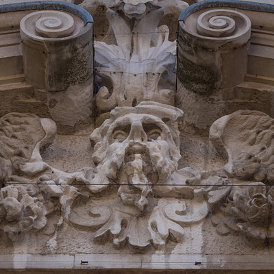 The image features a building with intricate carvings and decorations on its facade. There are several statues, including one of a man with a beard, which is prominently displayed in the center of the scene. Other statues can be seen throughout the building's exterior, adding to the overall artistic design.