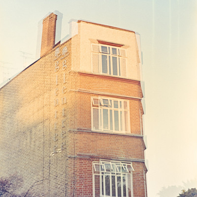 The image features a tall brick building with many windows. It appears to be an old, possibly historic structure. There are several small windows on the side of the building, and one large window at the top.