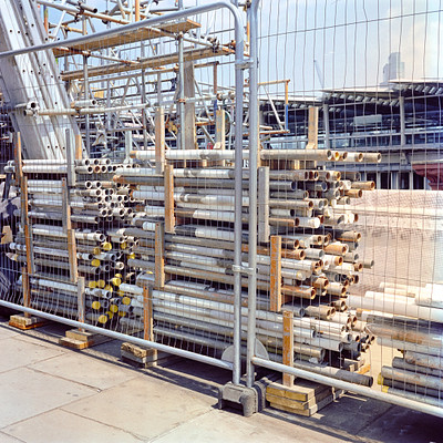 The image features a large pile of metal pipes and tubing stacked on top of each other. These pipes are arranged in various sizes, creating an impressive display. They are secured with fencing to prevent them from falling over or being moved by external forces.