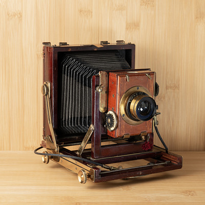 The image features an old-fashioned camera sitting on a wooden table. It is an antique, likely made of wood and metal, with a large lens at the front. The camera appears to be in good condition despite its age, and it has been placed on display for viewers to appreciate its craftsmanship and historical significance.