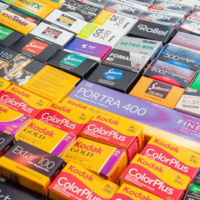 The image features a large display of various Kodak film products, including different types and colors. There are numerous boxes containing the films arranged in an appealing manner, showcasing their variety. Some of these boxes have distinctive colors, making it easy for customers to identify the specific type of film they're looking for.