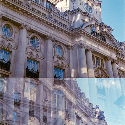 The image features a large, ornate building with many windows. It appears to be an old, historic structure with intricate details and architectural elements. A clock can be seen on the side of the building, adding to its charm.