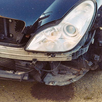 The image features a black car with its hood up, revealing the engine and front lights. The car appears to be in need of repair or maintenance, as it has a broken headlight on one side. There are also two other headlights visible, one on each side of the car.