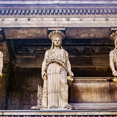 The image features a row of three statues, each depicting a woman with a different expression. They are positioned in front of an ornate structure, possibly a building or monument. Each statue is standing on a pedestal, and they appear to be part of the same artistic display.