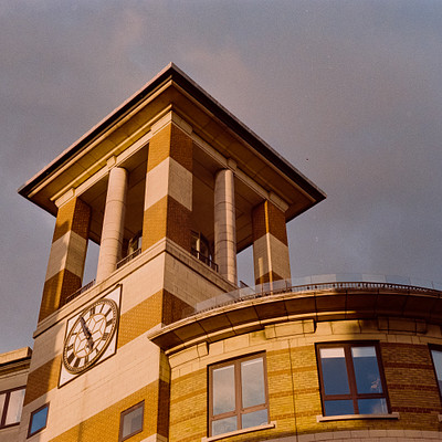 The image features a clock tower with a large clock on its side. The clock is positioned at the top of the tower, making it easily visible from a distance. The building has a brick exterior and appears to be an old structure.