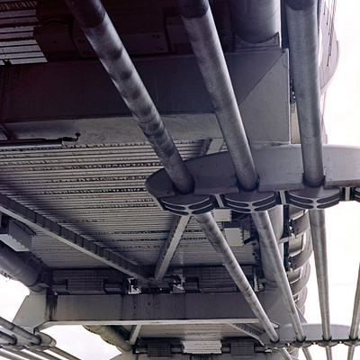 The image features a large metal structure with multiple pipes and beams. These pipes are connected to the main frame, creating an intricate network of support structures. The scene appears to be black and white, giving it a classic or vintage feel.