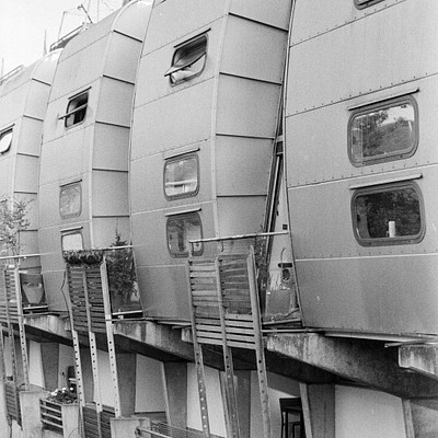 The image is a black and white photo of several tall buildings with many windows. These buildings are connected by walkways, allowing people to move between them easily. There are multiple balconies on the side of these buildings, providing additional space for residents or visitors.