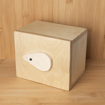 The image features a wooden box with a hole in the top, sitting on a table. The box is made of wood and has a handle for easy carrying. It appears to be a small storage container or a decorative piece, adding an element of style to the room it occupies.