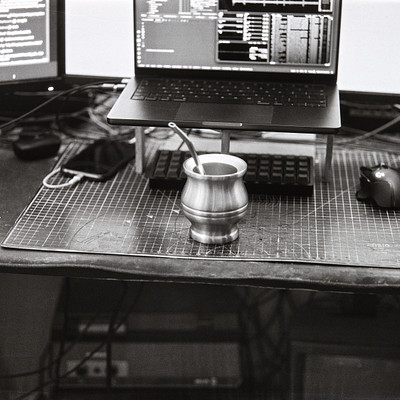 The image features a desk with various electronic devices on it. There is a laptop computer placed towards the center of the desk, and two keyboards can be seen in front of it. A mouse is also present near the right side of the desk.